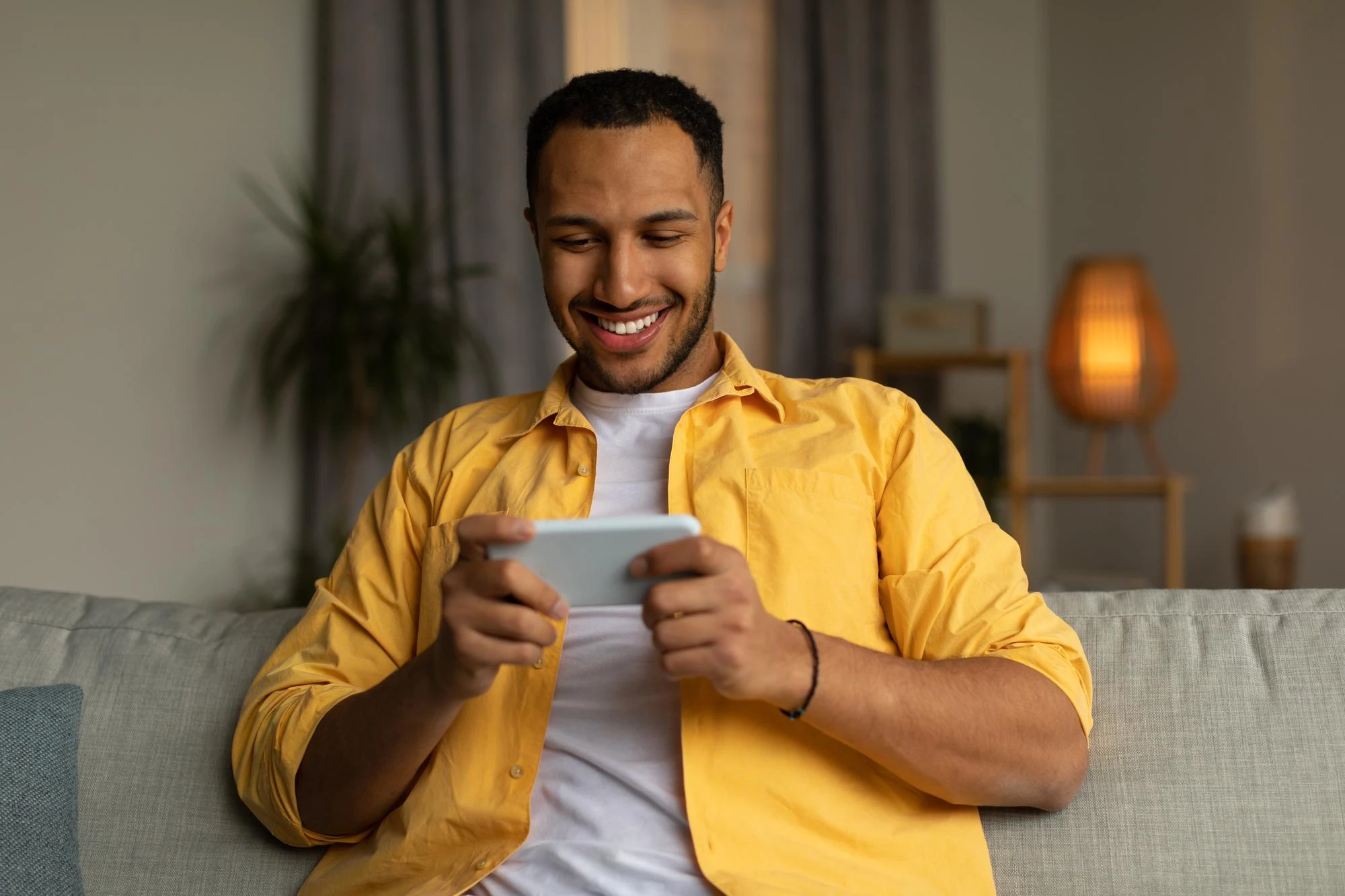 Homem assistindo pelo celular no sofá